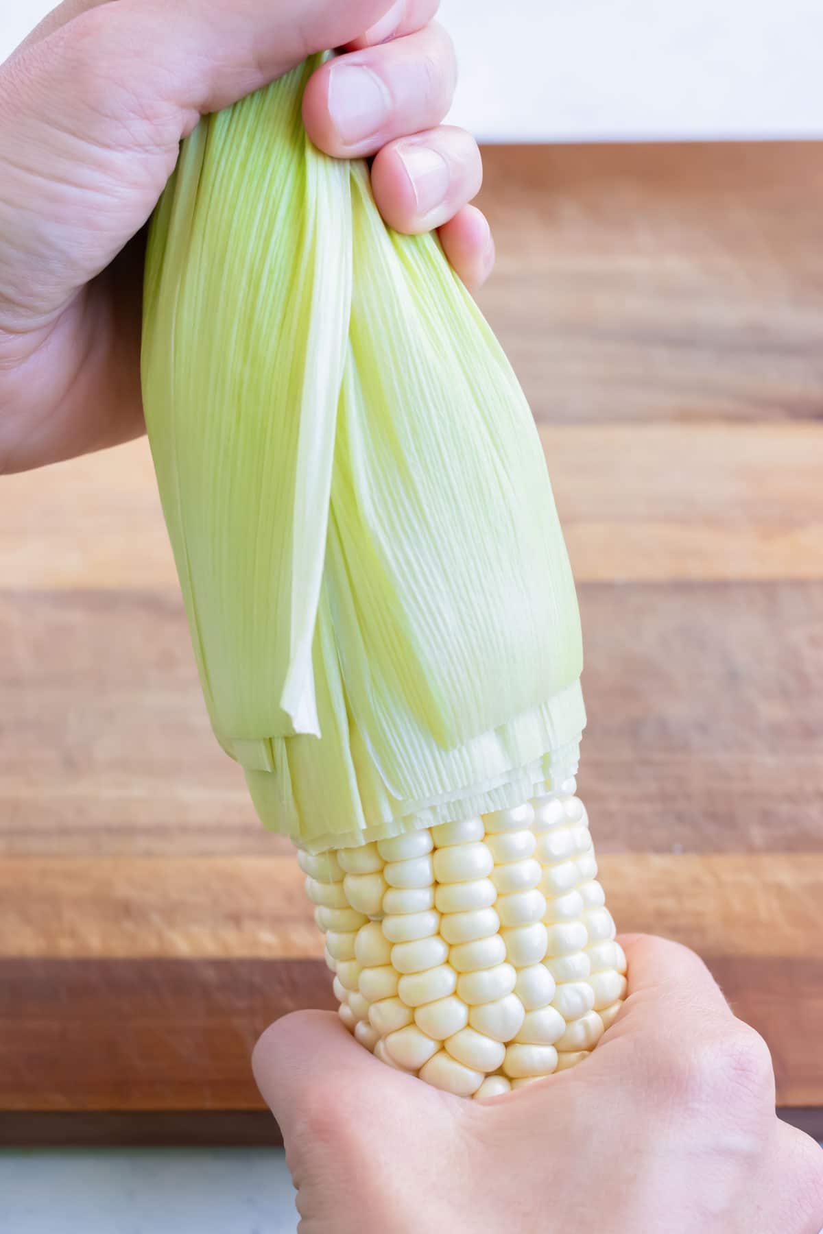 A piece of fresh corn is shucked.