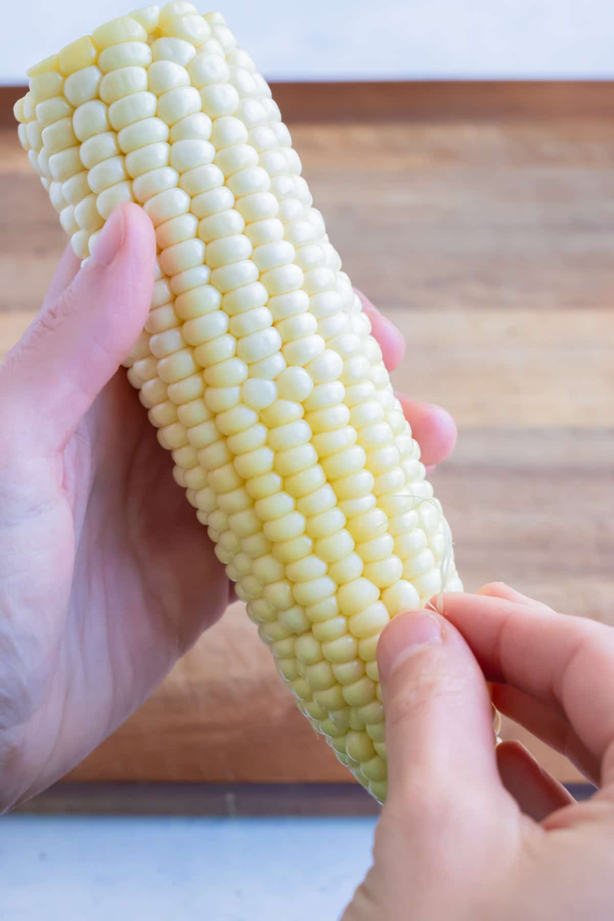 Remaining silk strands are removed from the corn.