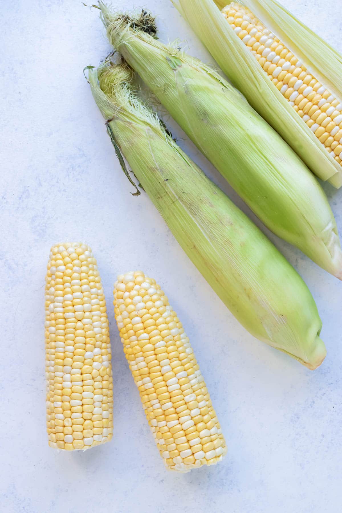 Corn with and without husks are shown on the counter.