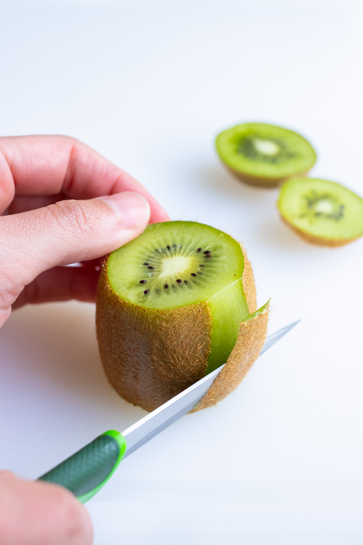 A small paring knife is used to peel the kiwi.