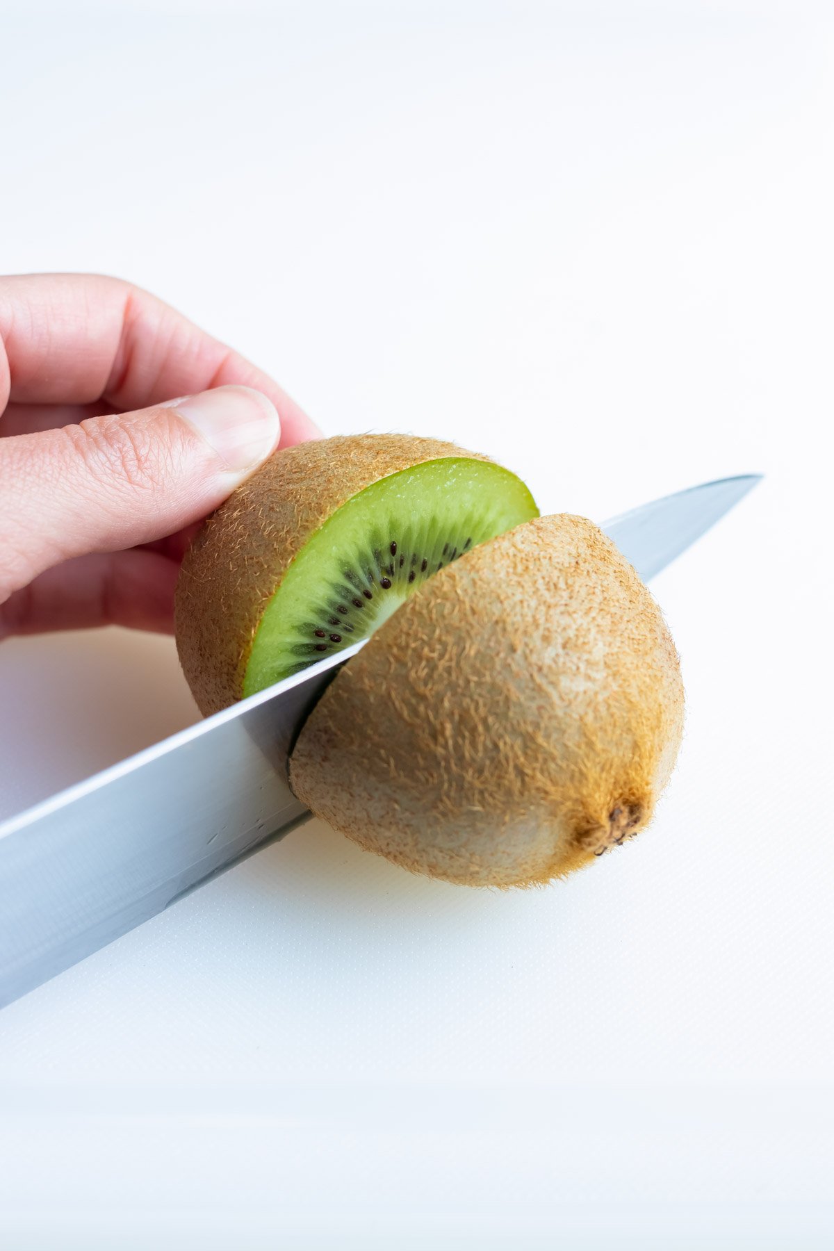 The kiwi is cut in half with a knife before peeling.