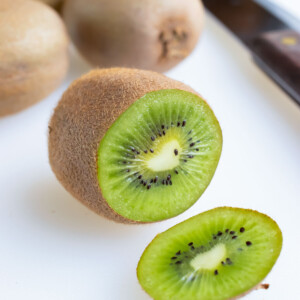 A kiwi with the end cut off is set on the counter next to a knife.
