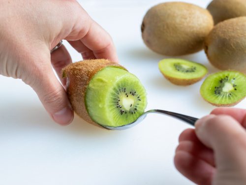 The kiwi fruit is removed from the skin with a metal spoon.