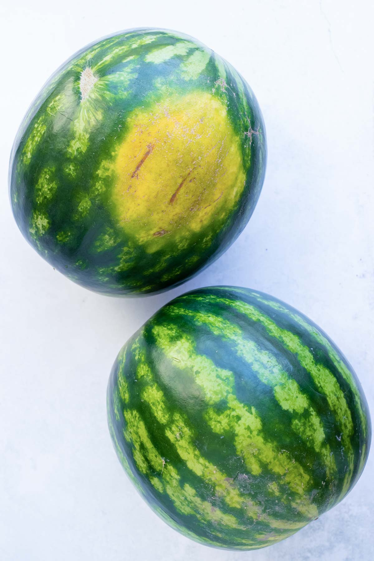 Whole watermelons, one with a big yellow spot.