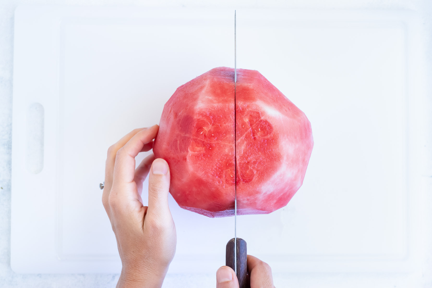 A sharp knife cutting watermelon flesh in half