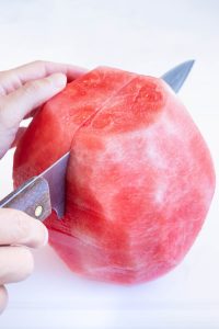 A sharp knife cutting watermelon flesh in half