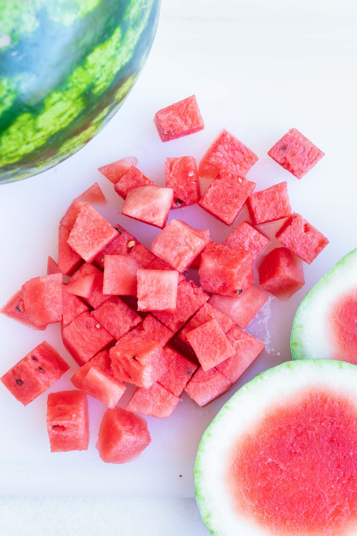 Cubed watermelon on a white cutting board.