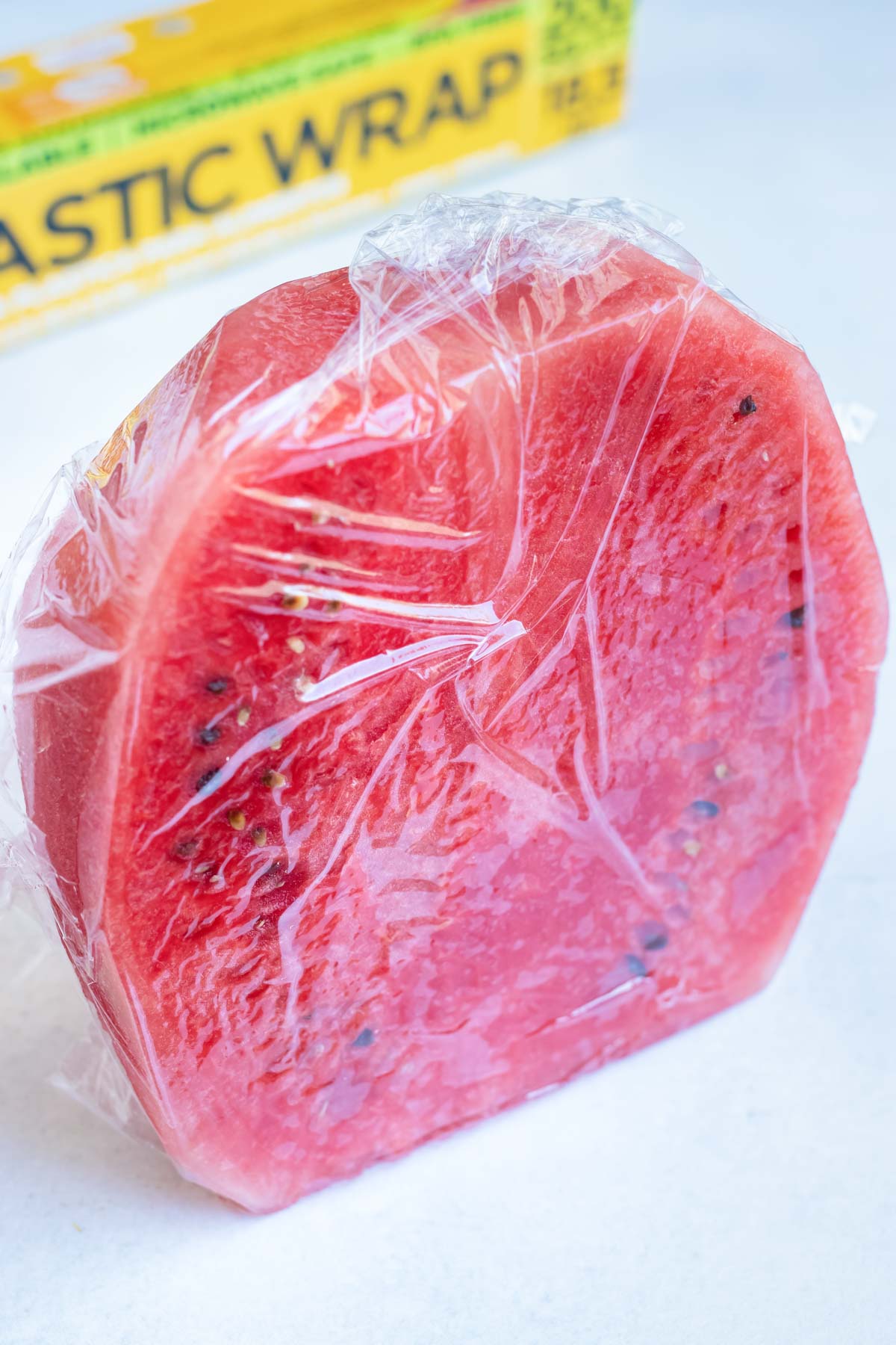 Half of a watermelon wrapped in plastic wrap to be stored in the refrigerator.