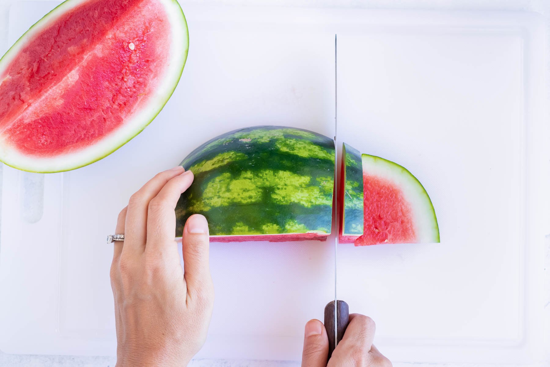 Slicing half a watermelon with the outside on.