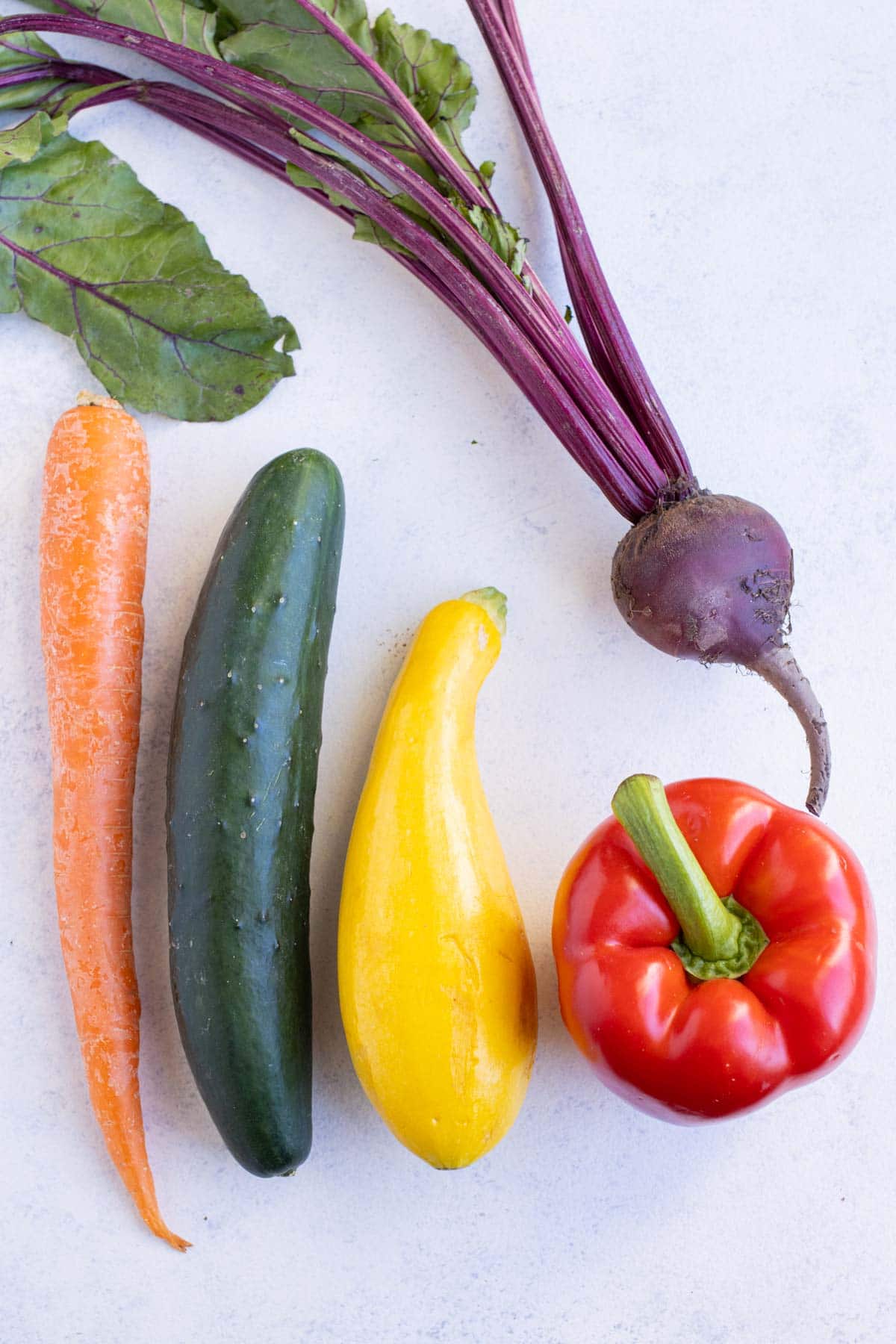 Bell peppers, carrots, cucumbers, beets, and squash are shown on the counter.