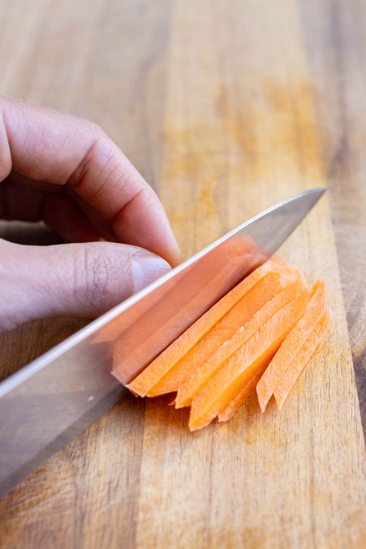 A sharp knife is used to cut carrots into strips.