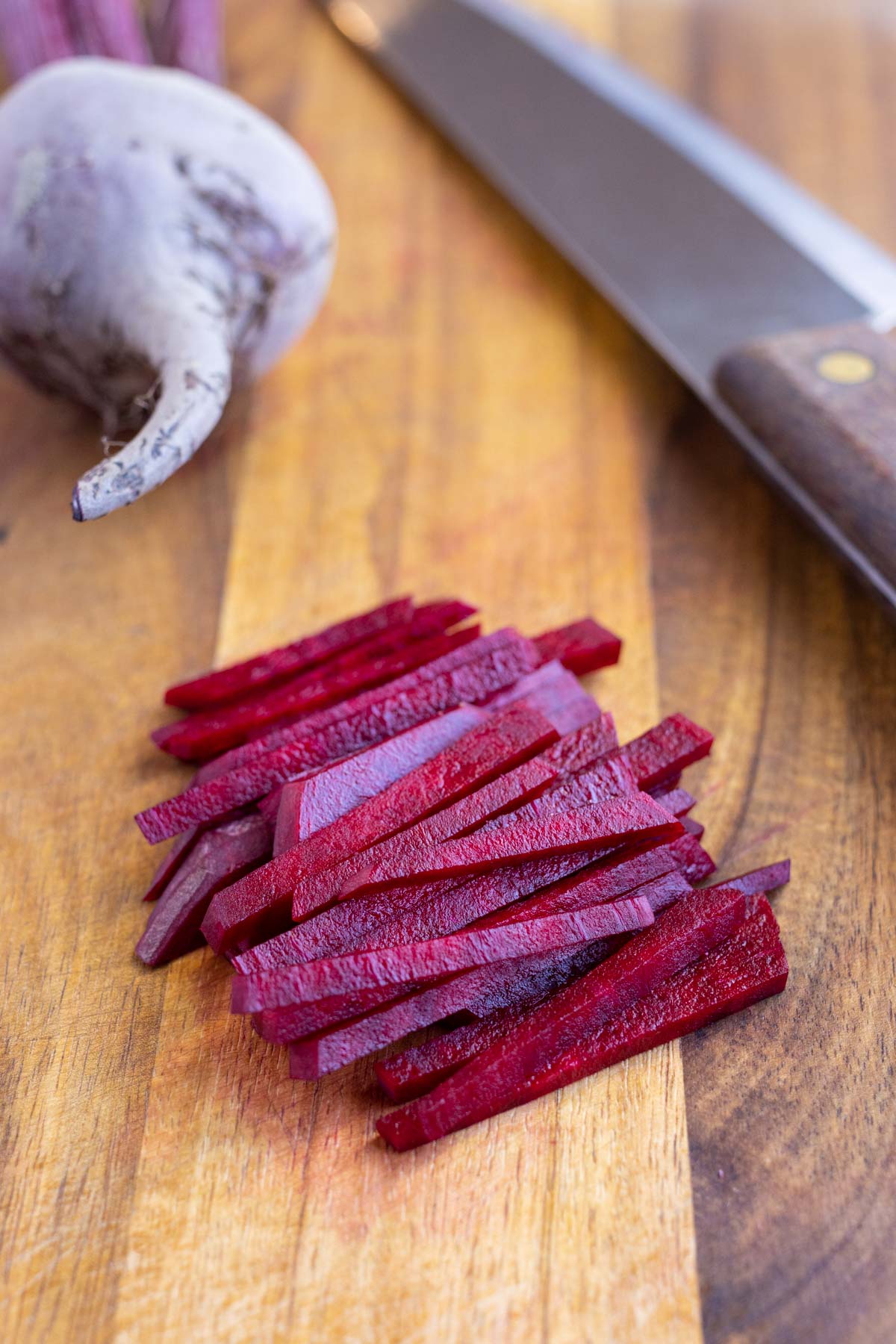 A pile of thinly cut beets is shown on the counter.