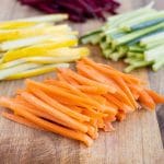 Julienne carrots, cucumbers, squash, and beets are shown on a cutting board.