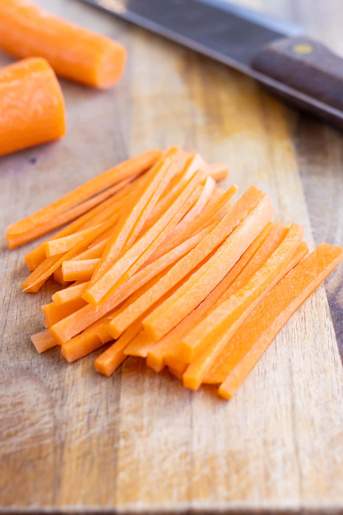 A pile of Julienne carrots are shown next to a knife.