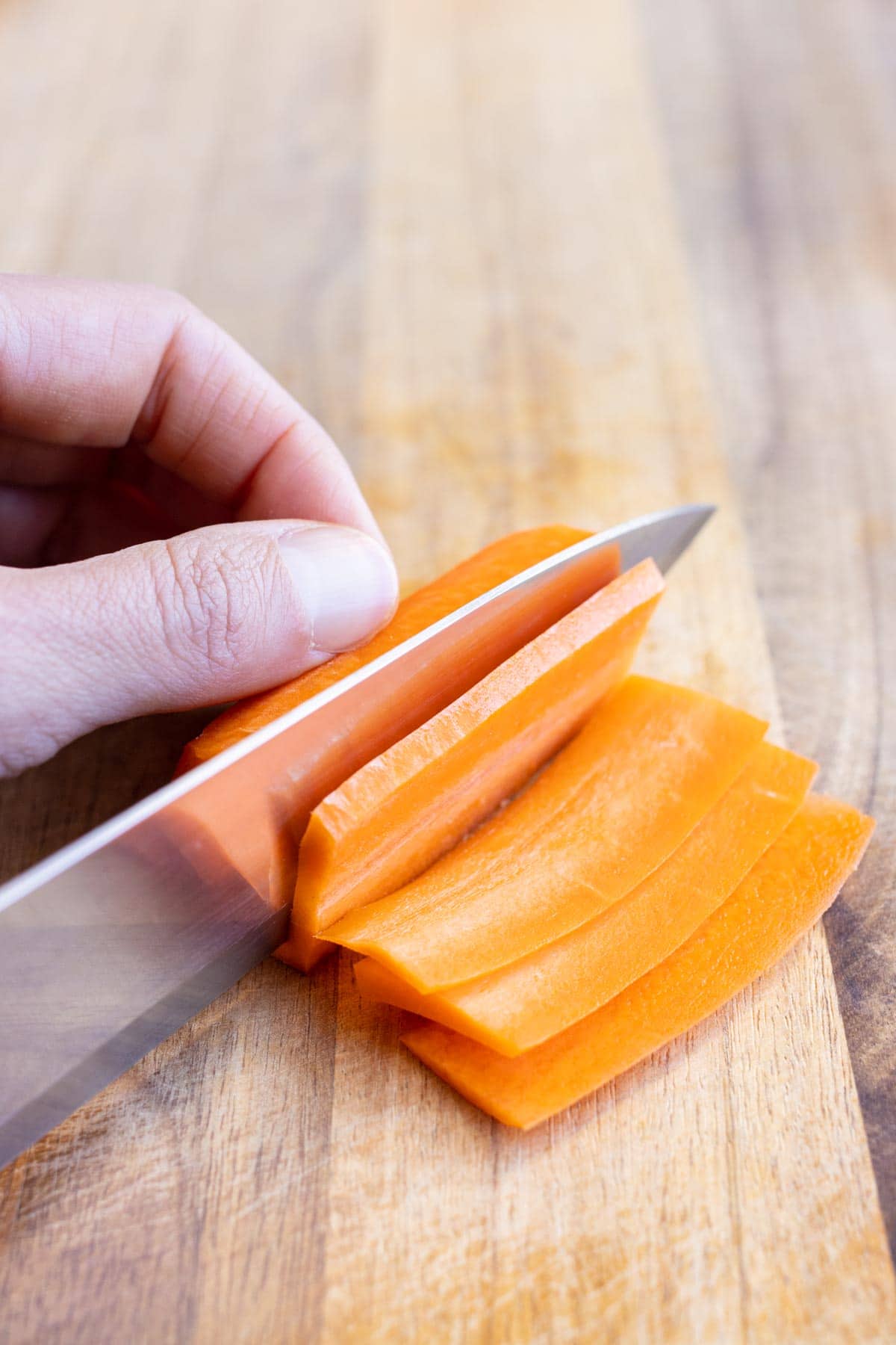 The raw carrot is cut into planks with a sharp knife.