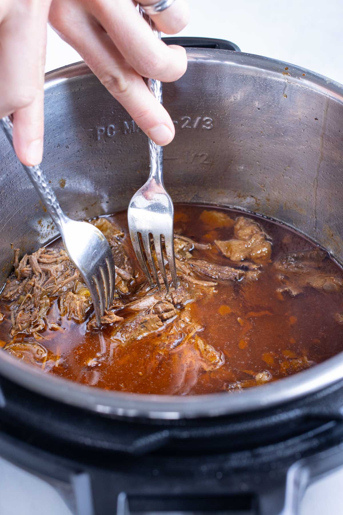 Beef is shredded after cooking in the pressure cooker.