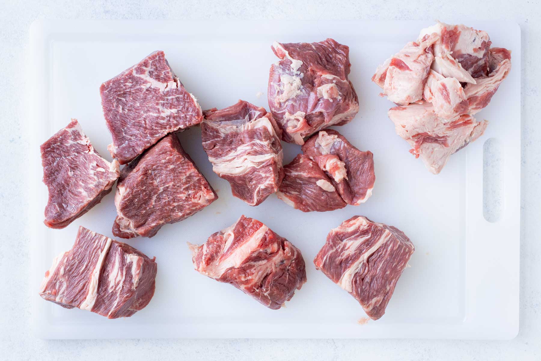 Chuck roast is cut into big chunks with a knife.