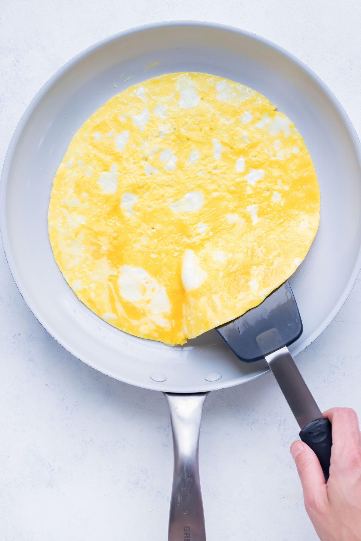 Eggs are cooked on the stove in a frying pan in one layer.