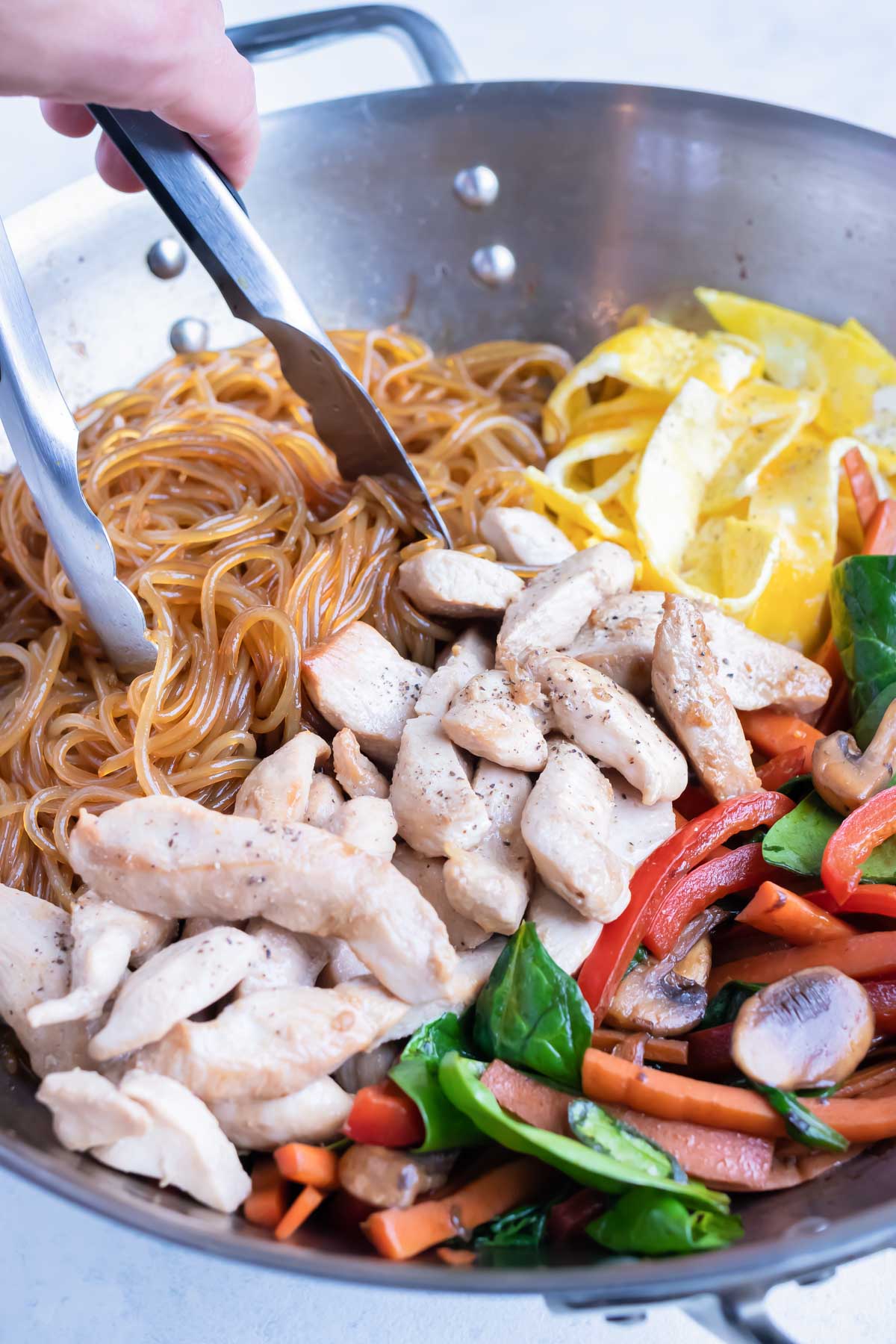 The cooked chicken, eggs, and cooked vegetables are combined with the glass noodles.