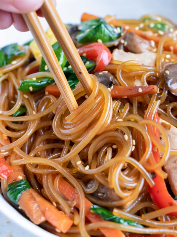 Glass noodles in a Japchae recipe are twirled by chopsticks.