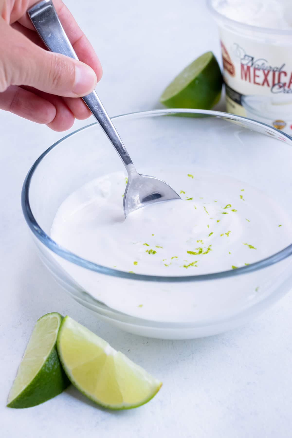 A spoon is used to mix the ingredients together for a lime cream fish taco sauce recipe.