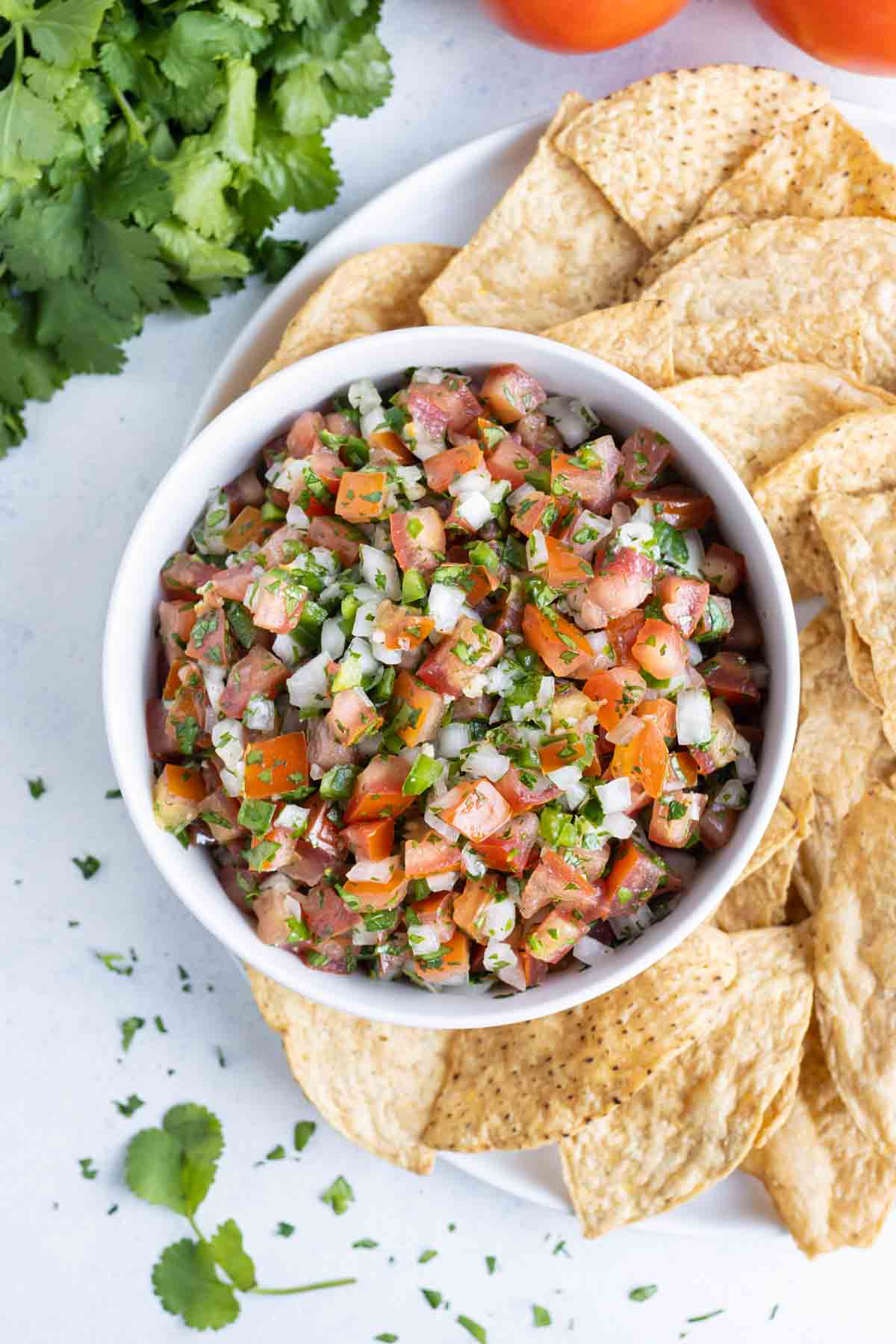 Pico de gallo is served with tortilla chips for a healthy Mexican appetizer.