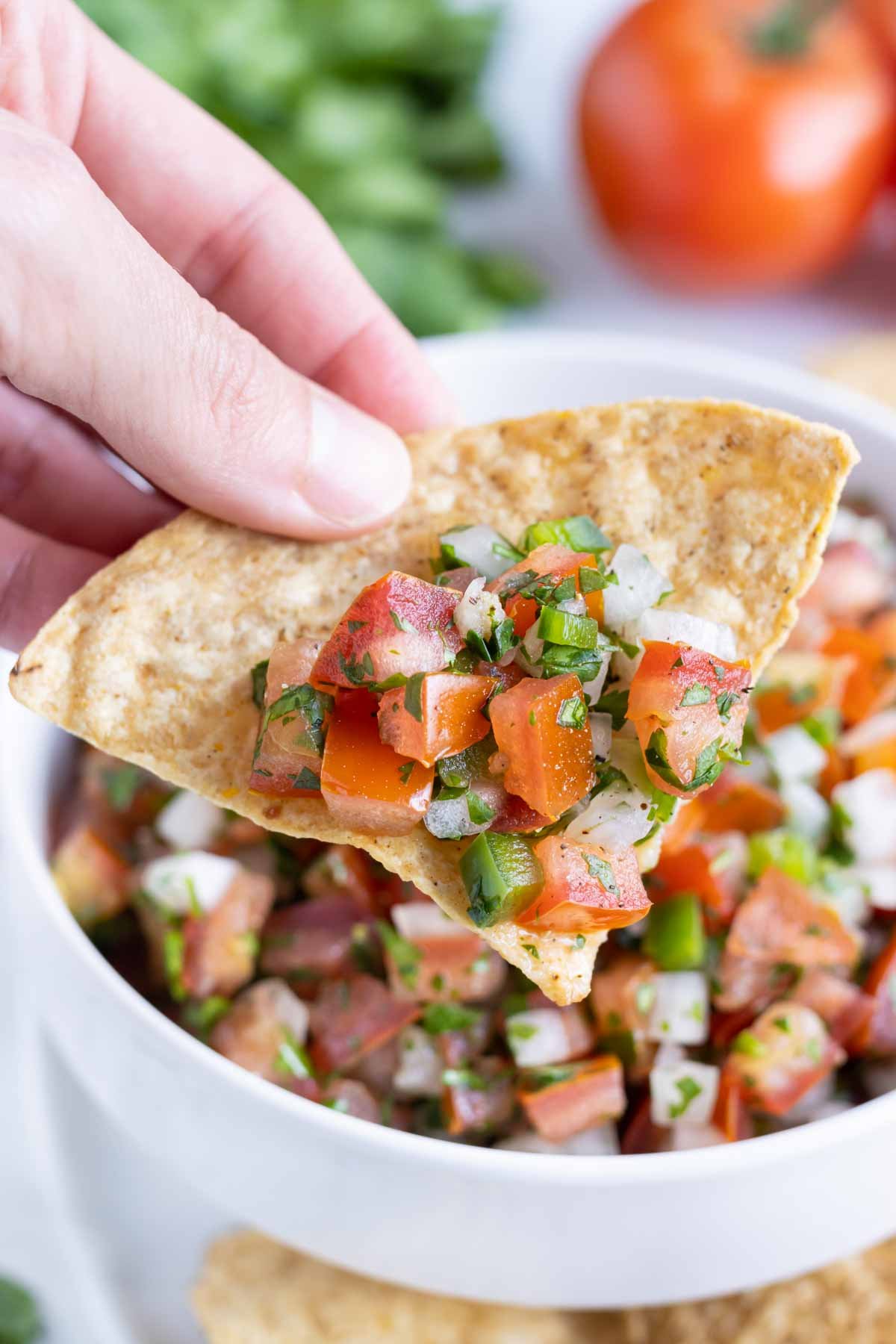 A tortilla chip is loaded with fresh and healthy pico de gallo.