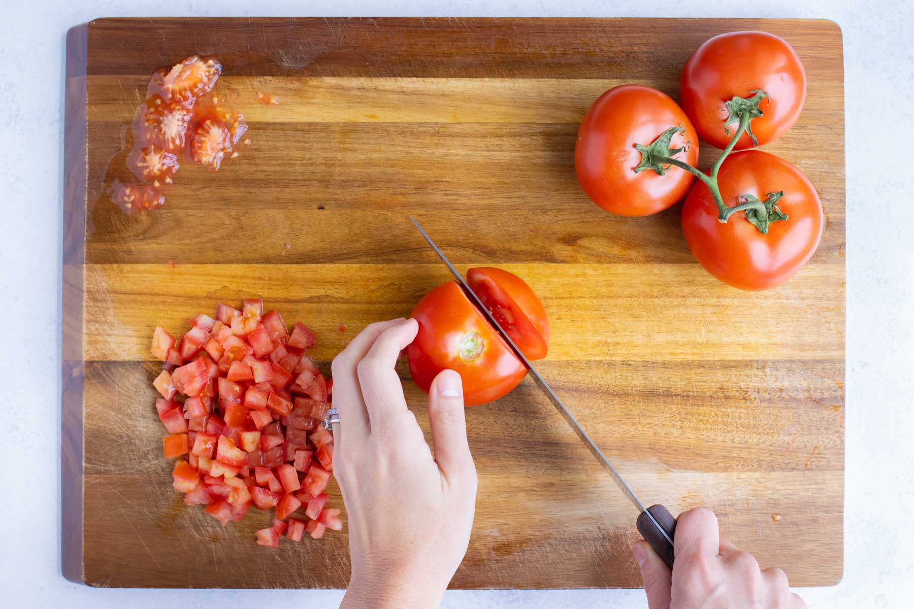 Tomatoes are chopped on a cutting board.