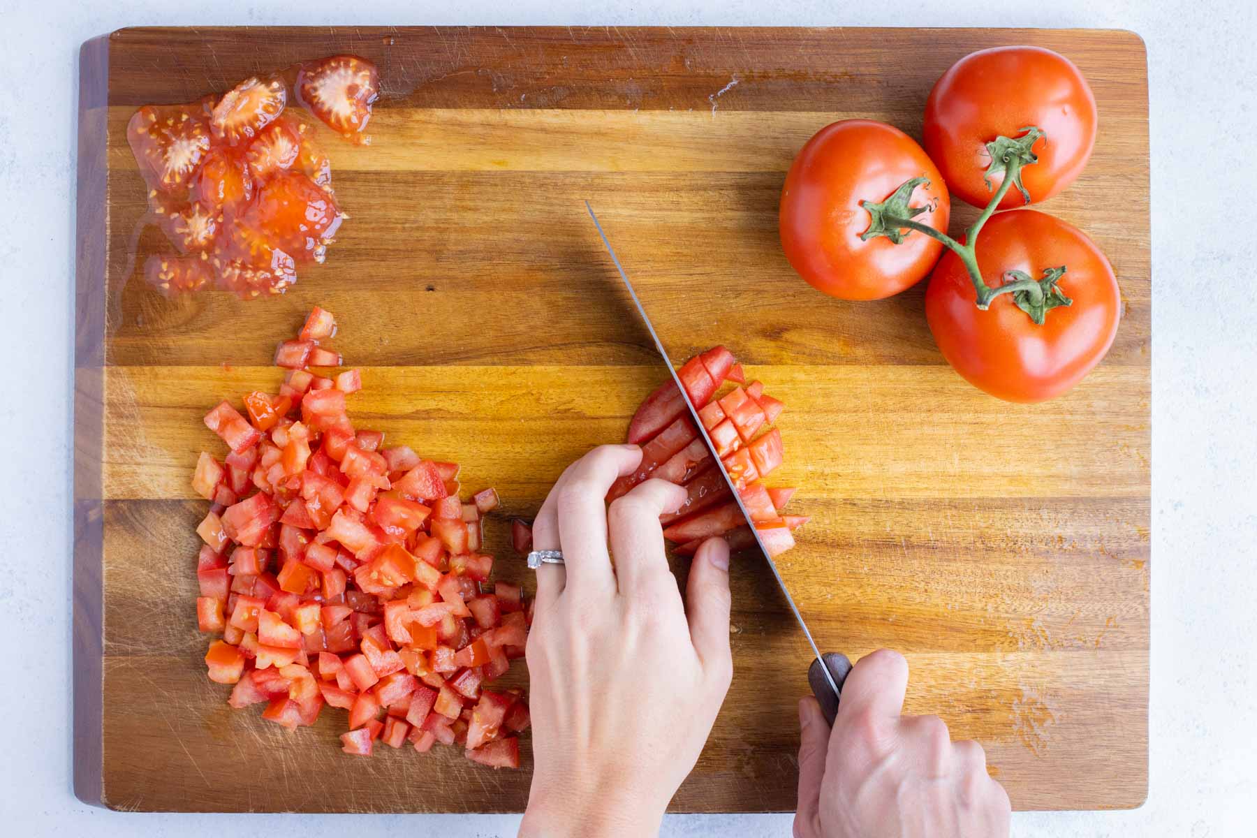 A sharp knife is used to cut the tomatoes into even sizes.