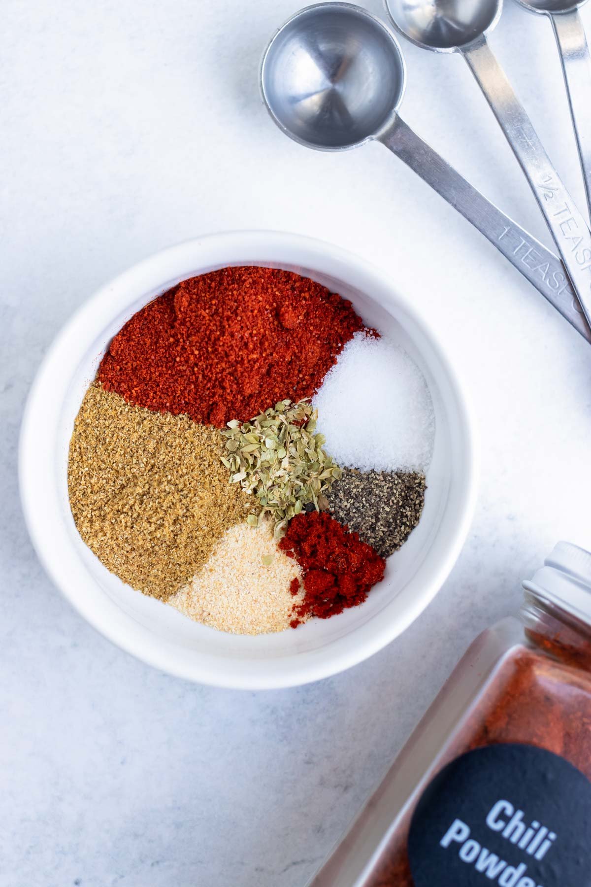 A white bowl with seasonings for an enchilada sauce.