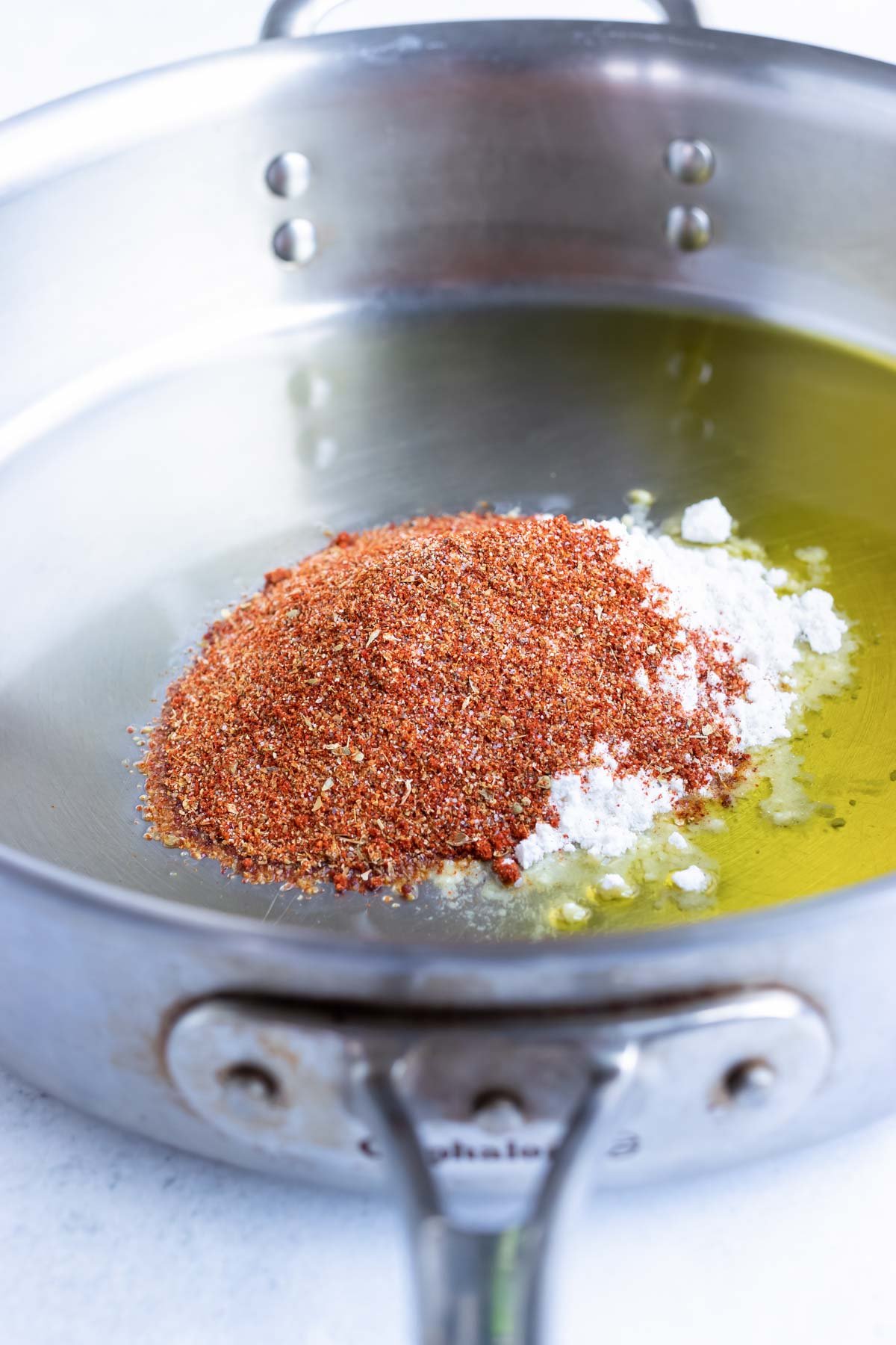 Adding ingredients to a skillet to make a roux.