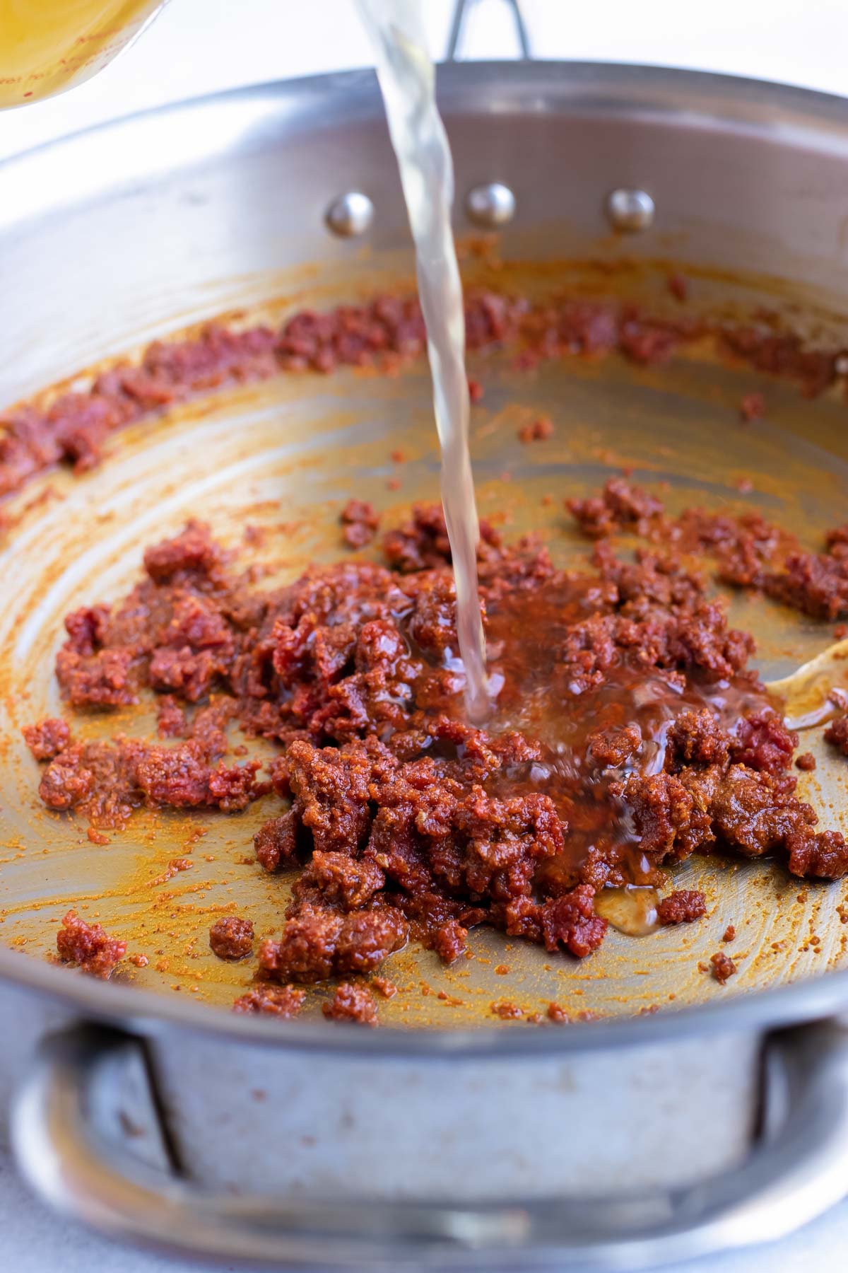 Pouring broth into an enchilada sauce base.