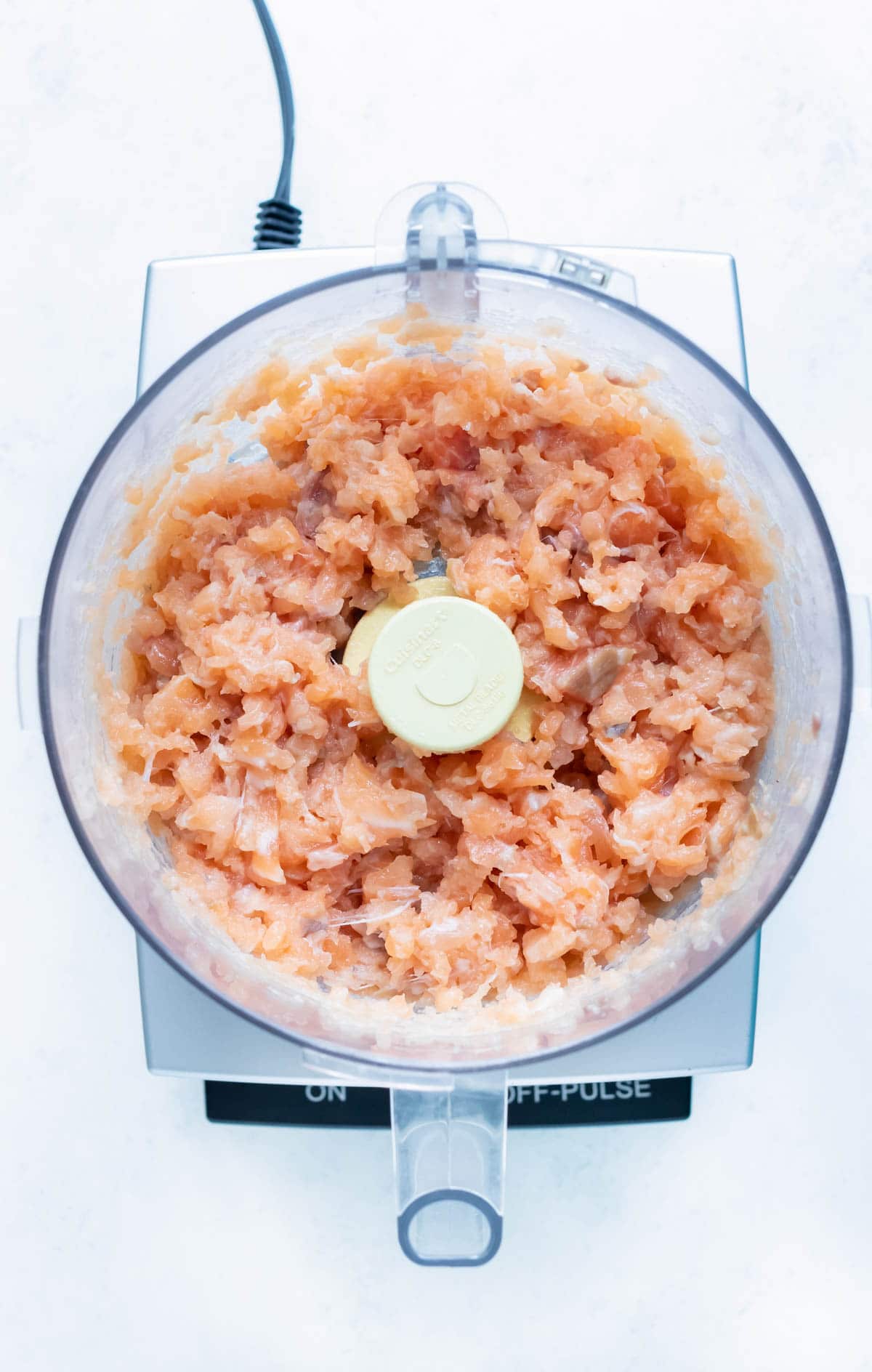 Salmon is finely chopped in a food processor.