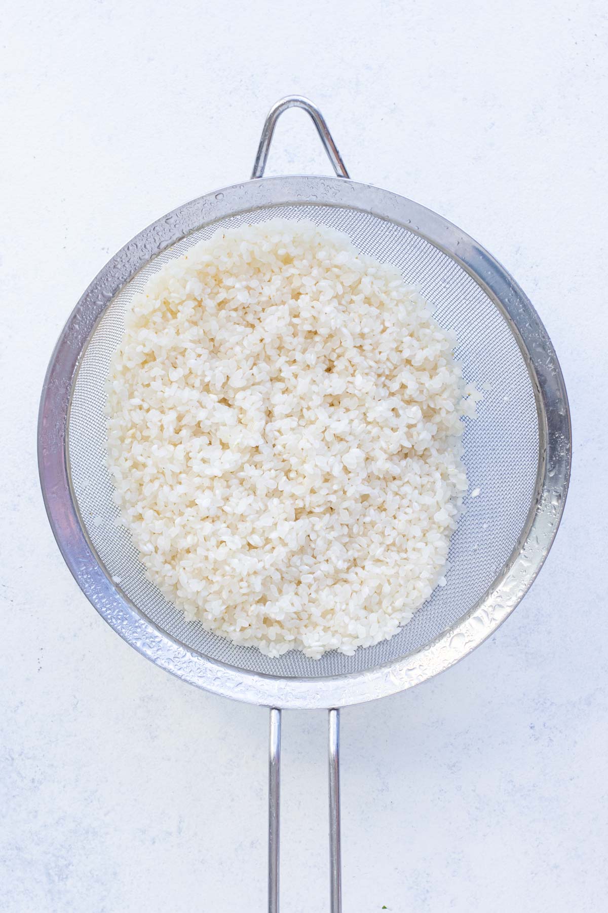 Rice is rinsed in a collander.