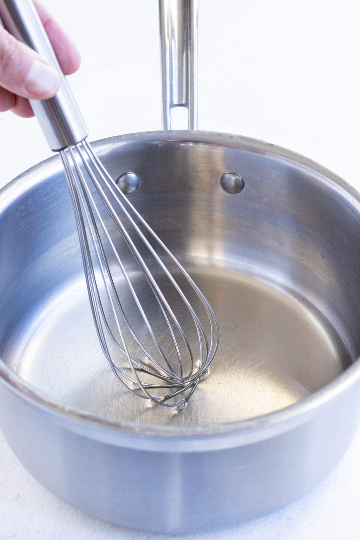 Vinegar, sugar, and salt are combined in a pan on the stove.