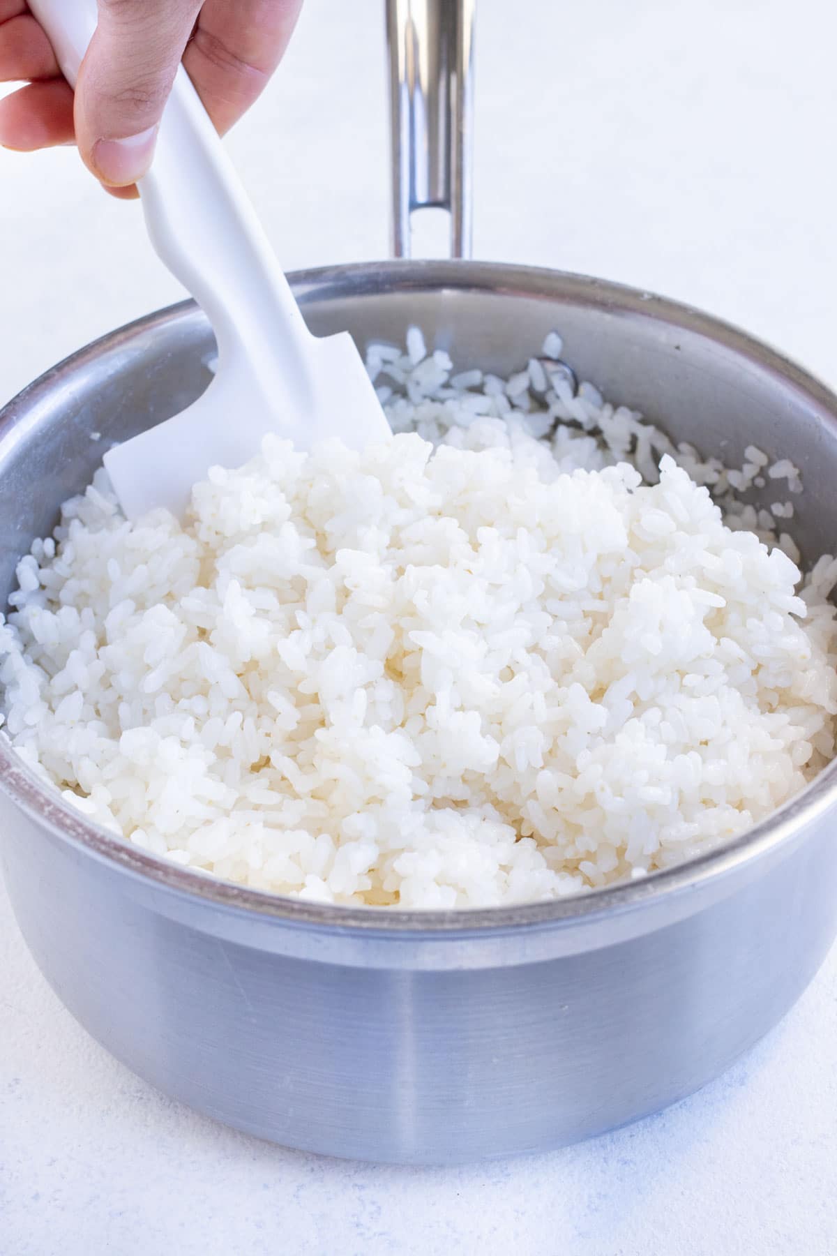 Sushi rice is mixed together with vinegar mixture.