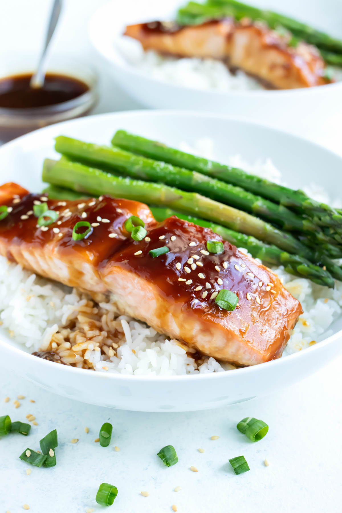 Teriyaki salmon is served on top of fluffy white rice.