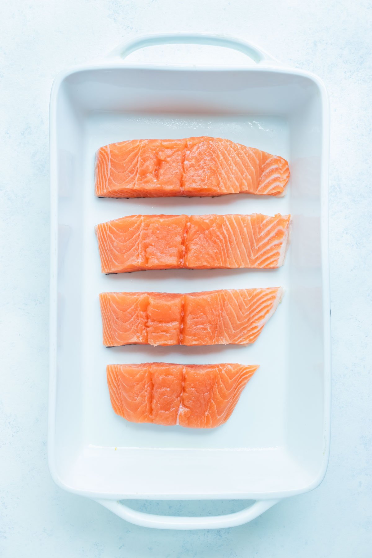 The four pieces of salmon are placed in a baking dish.