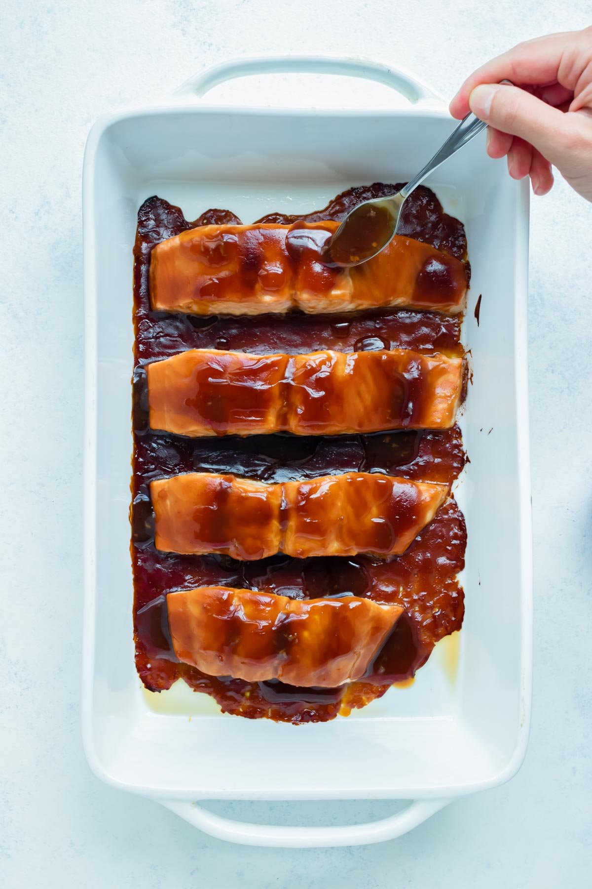 Teriyaki sauce is added to the salmon filets before being baked in the oven.