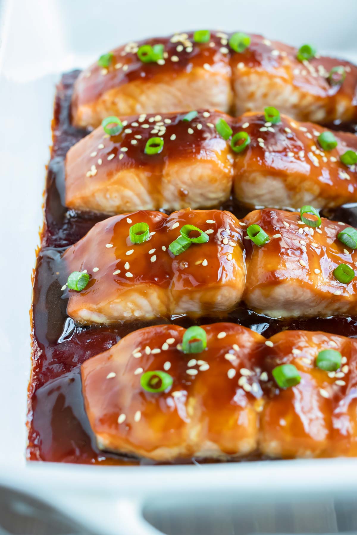 Healthy teriyaki salmon is served from a white baking dish.