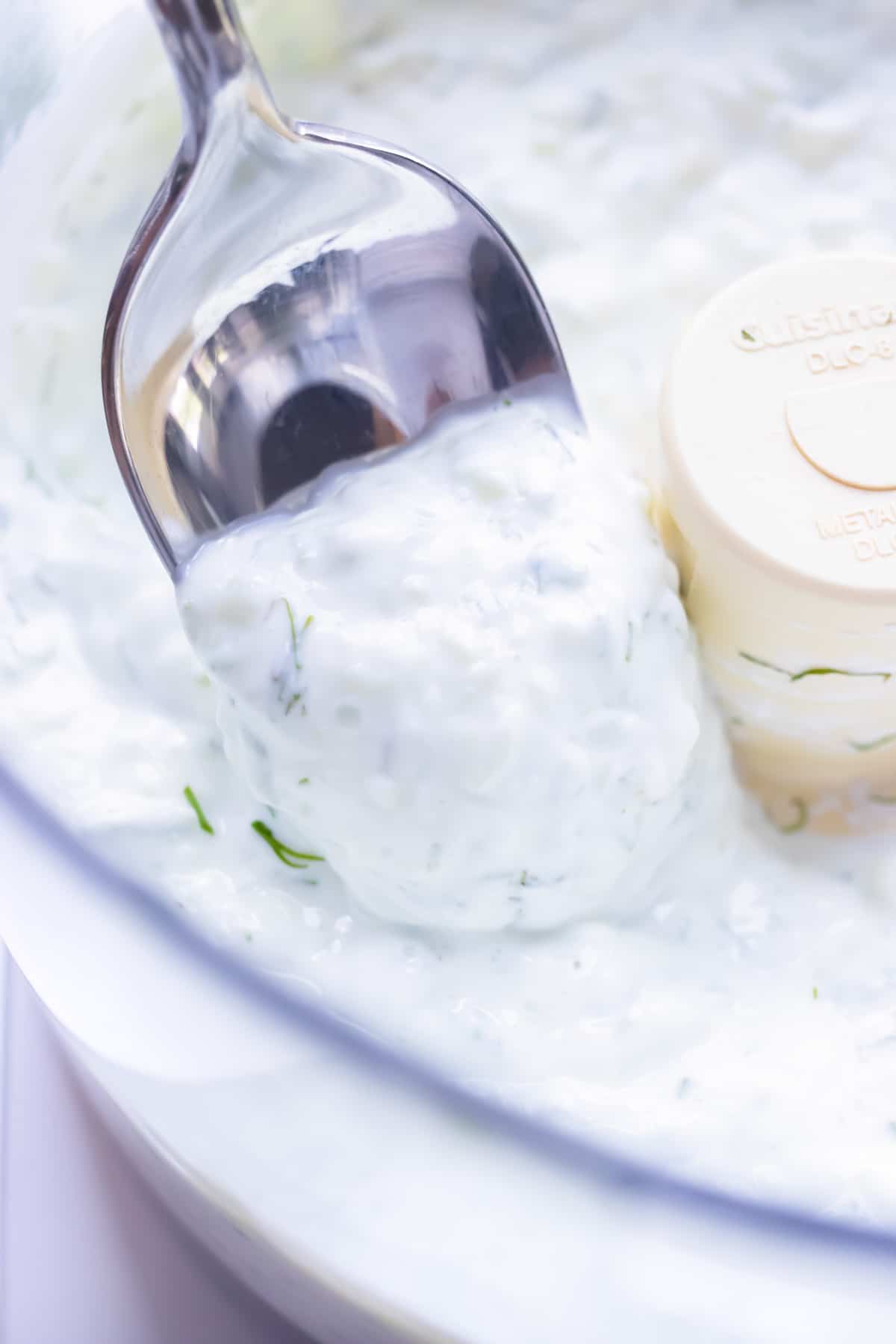 Use a spoon to remove low-carb Mediterranean dip from the food processor in preparation for serving.