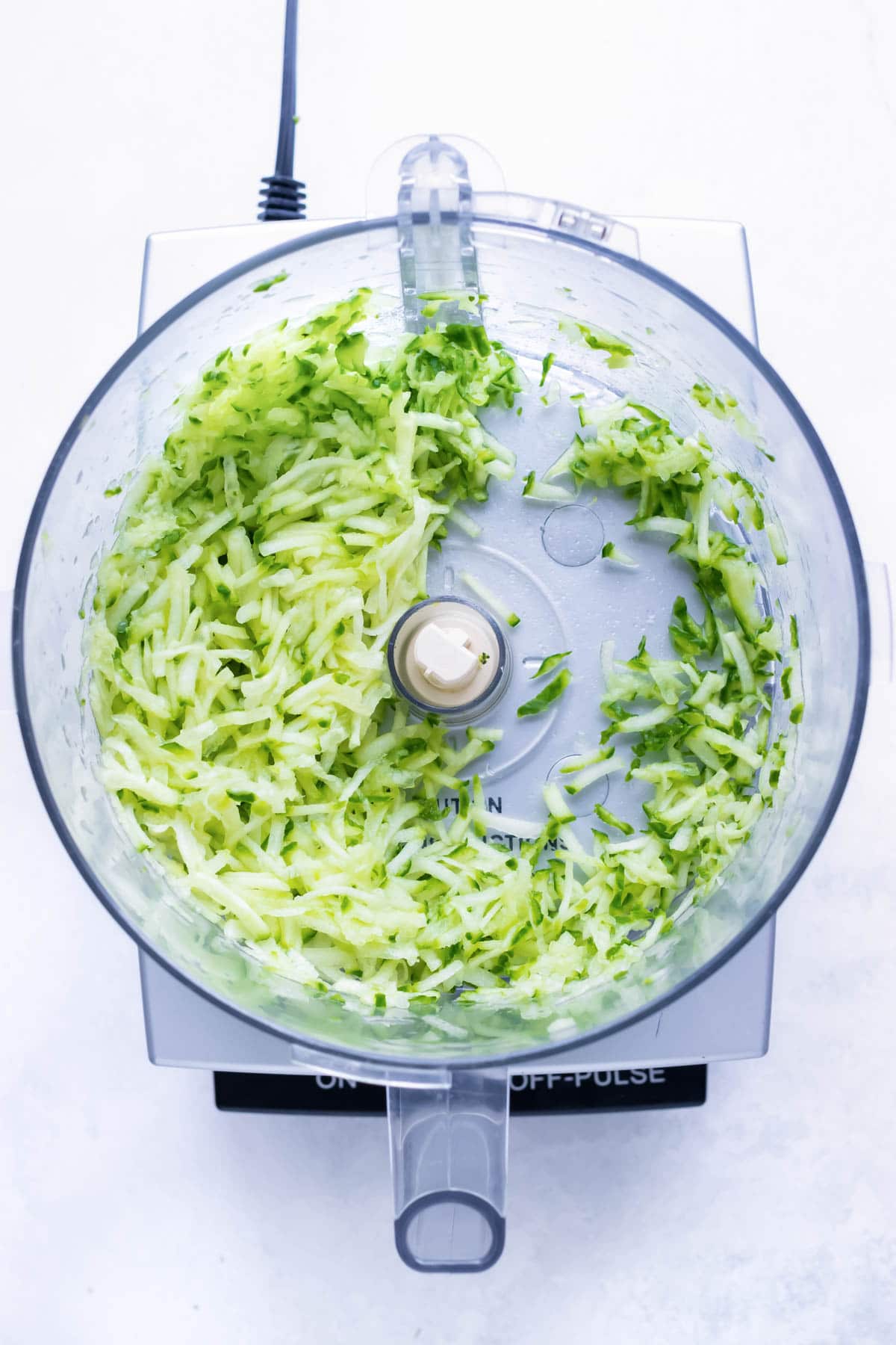 Cucumber is shredded in a large food processor