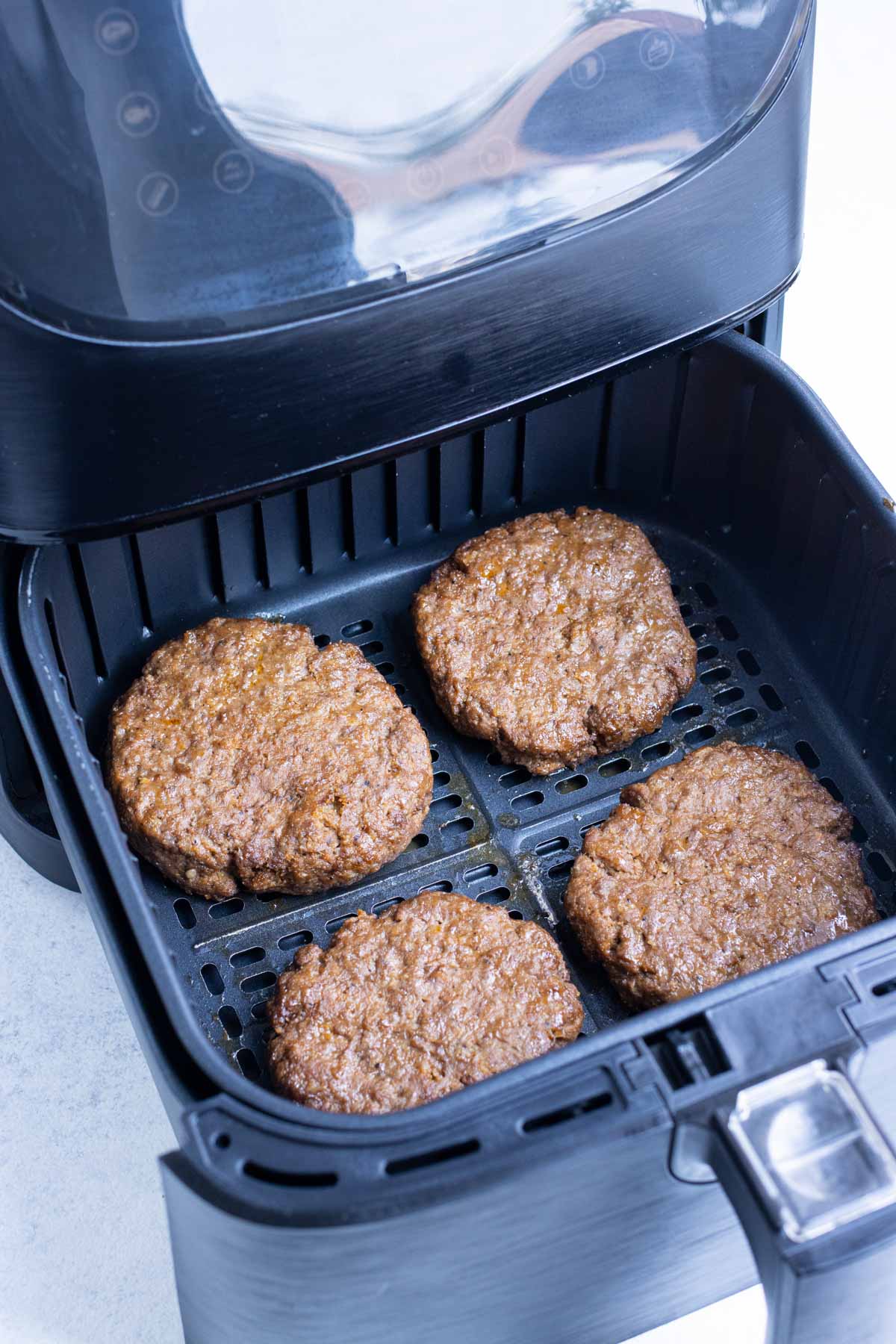 Air fryer hamburger patties are cooked until brown on the outside.