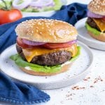 A hamburger is dressed with tomatoes lettuce and red onion on a gluten-free bun.