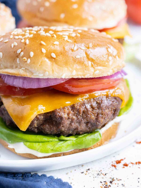 An air fryer cheeseburger is shown on a white plate.