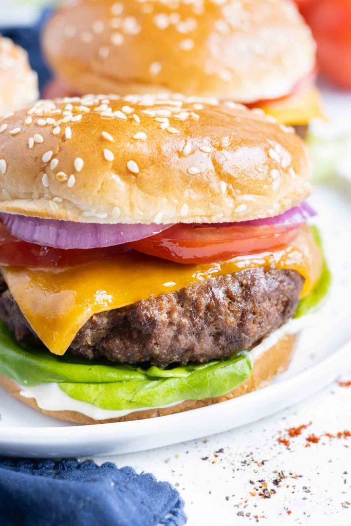 An air fryer cheeseburger is shown on a white plate with a homemade burger seasoning.
