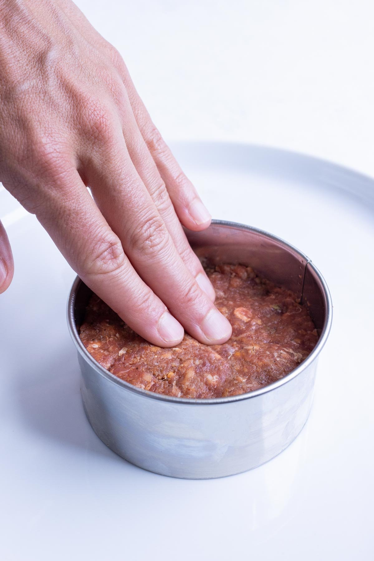 Meat is formed into patties using a round cutter.