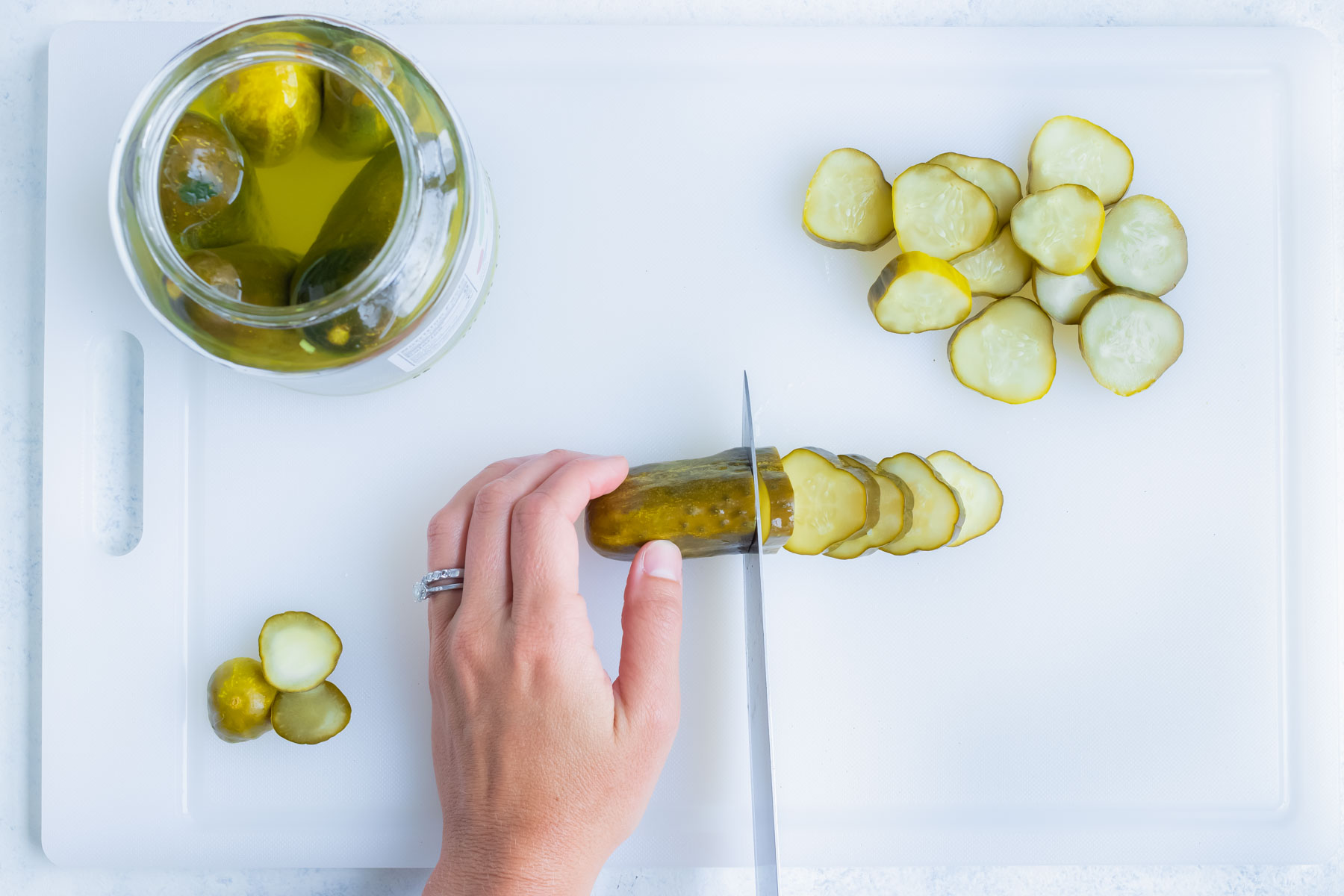 A dill pickle is sliced with a knife.