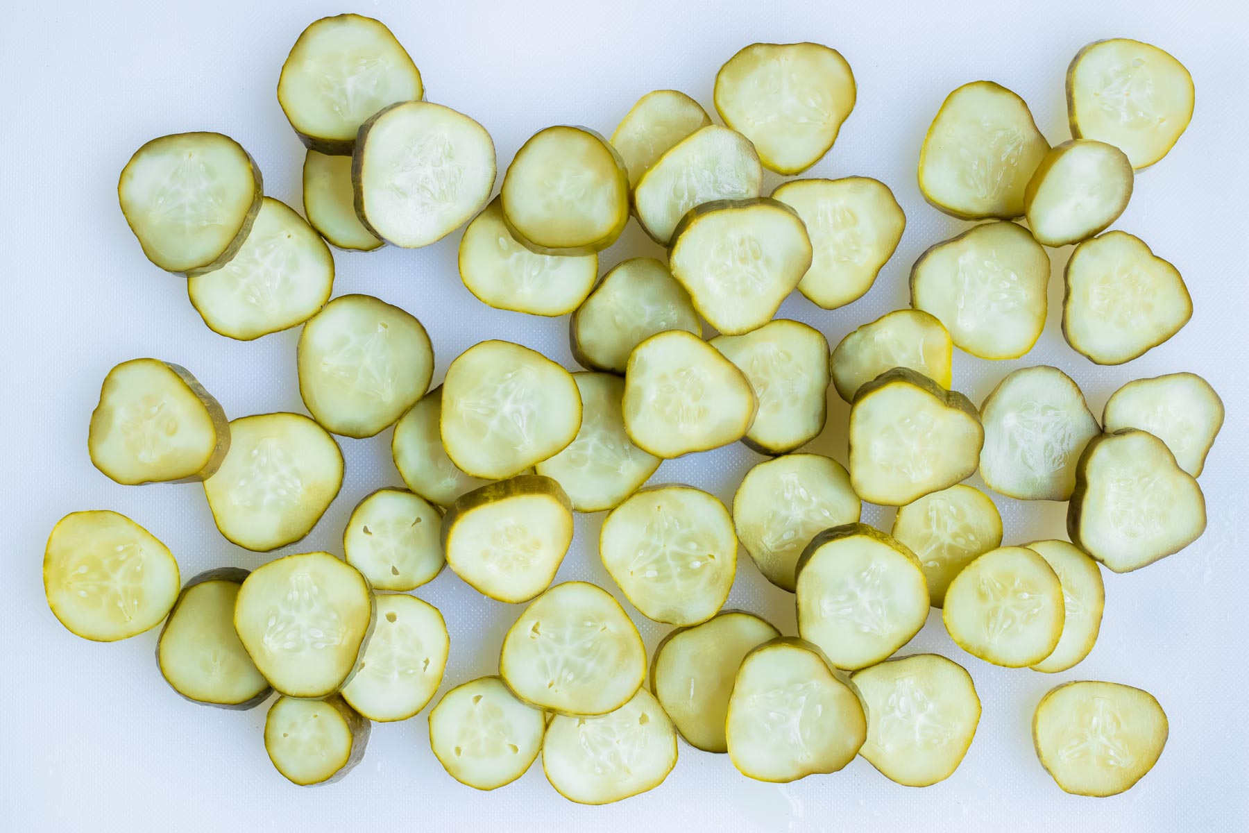 The sliced pickle chips are laid out on the counter.