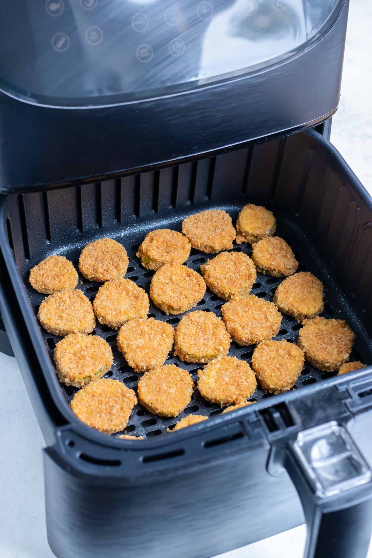 The coated pickles are laid in a single layer in the air fryer.